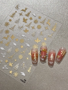 Macro shot of silver embossed Christmas nail decals with snowflakes and reindeer motifs