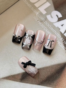 Macro view of long rectangular press-on nails with black 3D bows and white lace details