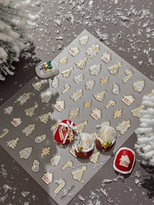 Macro detail of 3D embossed gold Christmas nail stickers with snowmen and reindeer
