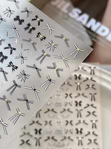 Macro detail of bow nail stickers with gold accents in black, white, and striped patterns