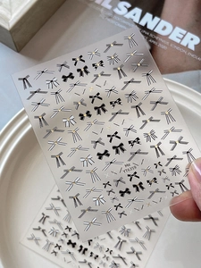 Detail of gold-stamped bow nail stickers with black and white patterns and gold dots