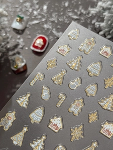 Close-up of 3D embossed Christmas nail art stickers with golden tree and snowman motifs