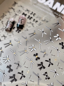 Macro shot of black and white bow nail stickers with gold dot accents and star patterns