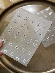 Dettaglio di adesivi per unghie a fiocco 3D argento YT5594 su carta smerigliata lucida