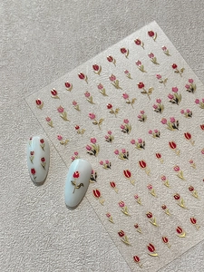 Détail de stickers à ongles tulipes dorés avec fleurs rouges et modèles blancs