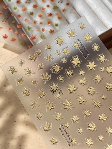 Macro shot of gold embossed maple leaf nail stickers with Chinese calligraphy art