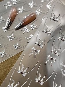 Dettaglio macro di adesivi per unghie con fiocco metallico 3D e texture in rilievo