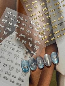 Detail of silver and gold bow nail art stickers applied on luxury cat-eye manicures