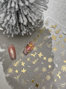 Detail of silver Christmas nail stickers featuring gold snowflakes and reindeer patterns