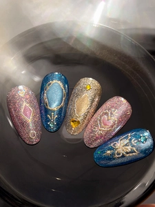 Macro detail of luxury press-on nails with blue cat-eye effect and butterfly 3D charms