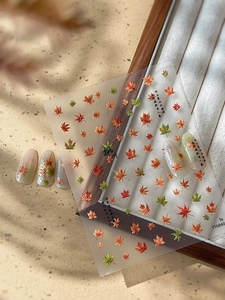 Detail of maple leaf nail stickers with Chinese calligraphy and autumn-themed designs