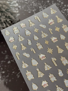 Macro shot of glittery Christmas nail stickers with gold foil trees and gingerbread houses