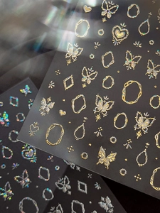 Macro detail of gold laser butterfly and heart 3D nail stickers with metallic finish