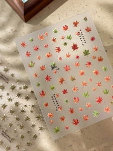 Detail of maple leaf nail stickers with Chinese calligraphy and autumn gradient colors