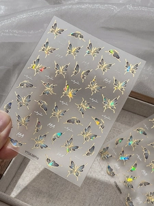 Detailed macro view of laser butterfly nail art stickers with gold foil edges and sparkles