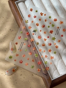 Macro detail of maple leaf nail stickers with Chinese poetry and autumnal patterns