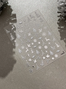 Detail view of 5D white embossed Christmas nail stickers with reindeer and snowflake patterns