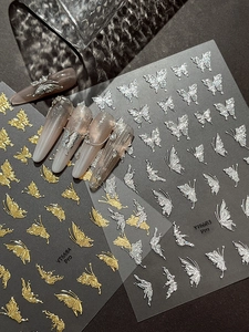 Macro detail of 3D butterfly nail art stickers with silver and gold metallic texture
