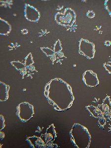 Macro shot of 3D embossed silver laser nail stickers with butterfly and heart patterns