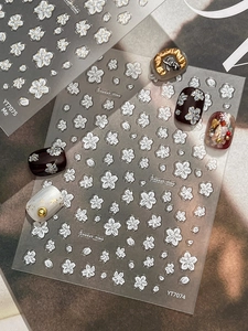 Macro detail of 3D embossed white floral nail art stickers on various base colors