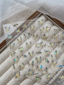 Detail shot of blue shell butterfly nail stickers with gold foil edges on velvet