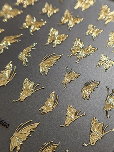 Macro detail of 3D embossed golden butterfly nail art stickers with metallic foil finish