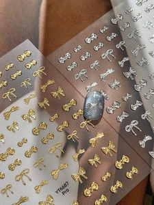 Detail of silver metallic bow nail sticker with 3D embossed texture on blue cat eye nails