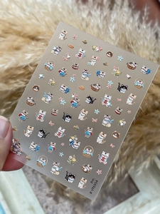 Detail of cute 3D cartoon cat nail stickers with pearl accents and floral patterns