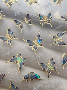 Macro view of blue butterfly nail stickers with gold outlines and iridescent laser effect