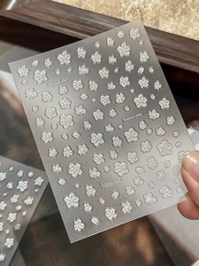 Macro detail of 3D embossed white cherry blossom nail art stickers with gold foil edges