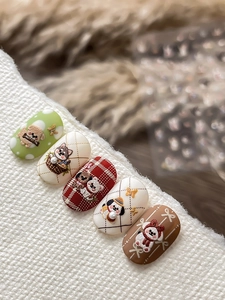 Close-up of 3D embossed nail art with cute cartoon dogs, pearls, and bows on knit background