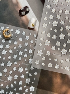 Detailed macro view of 3D embossed white cherry blossom nail stickers with gold edges