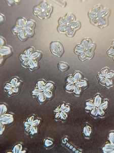 Detailed macro view of 3D embossed white floral nail stickers with golden outlines