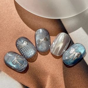 Blue cat eye press-on nails with silver bow charms and intricate lace patterns