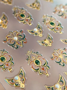 Detailed macro view of 3D baroque nail stickers with gold patterns and micro pearls