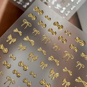 Golden 3D bow nail stickers featuring embossed metallic ribbon designs for DIY manicure art