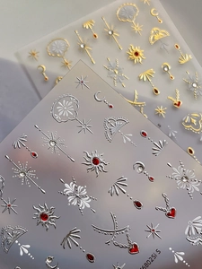 Macro view of 3D metallic sun moon and star nail stickers with red gems texture