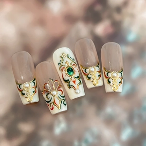 Vintage palace style press-on nails with gold embossed patterns and green gemstones