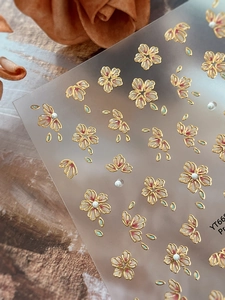 Detailed close-up of cherry blossom nail stickers with gold foil and 3D pearls