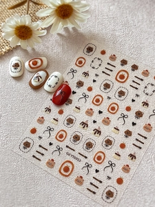 Détail macro de stickers ongles ours et nœud avec décor floral sur fond blanc pur