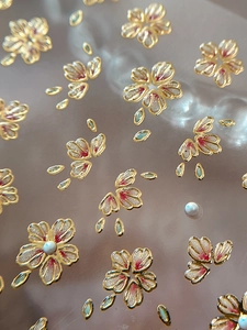 Macro detail of cherry blossom nail stickers with gold foil edges and white pearl accents