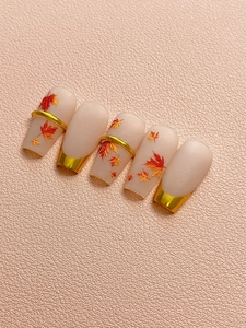 Detail of matte autumn maple leaf nail stickers with gold accents and metallic rings
