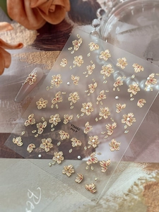 Detail of 3D nail art stickers with golden cherry blossoms and pearl embellishments