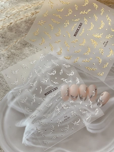 Detail view of gold embossed 3D leaf nail stickers with intricate metallic textures