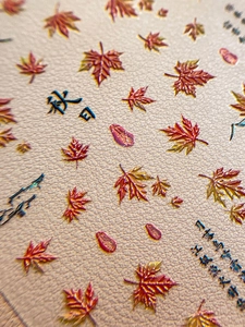 Macro detail of 3D embossed autumn maple leaf nail art stickers with relief texture
