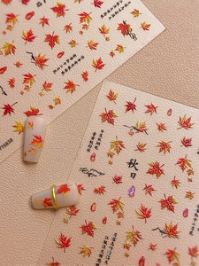 Detail of red and yellow maple leaf nail art stickers with autumn calligraphy elements