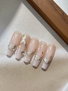 Détail de faux ongles dégradé rose nude avec texture 3D argentée, étoiles et perles
