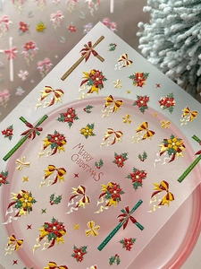 Vista macro di adesivi 3D per unghie natalizi con motivi di fiocchi e fiori di stella di Natale