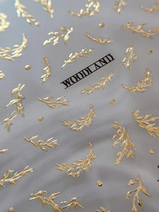 Macro detail of woodland gold embossed leaf nail stickers with metallic 3D texture