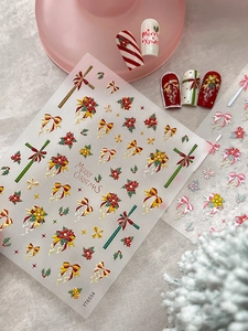 Dettagli di adesivi per nail art natalizi con fiocchi in rilievo 3D e motivi di agrifoglio